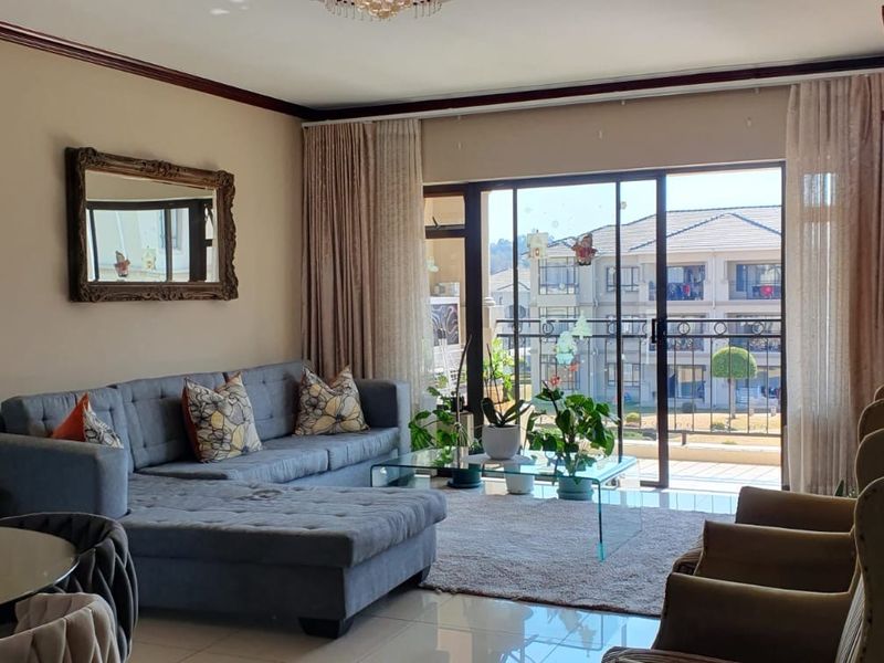 A well-lit living room featuring tiled flooring, crown molding, and a large sliding glass door providing access to a balcony with neighborhood views.
