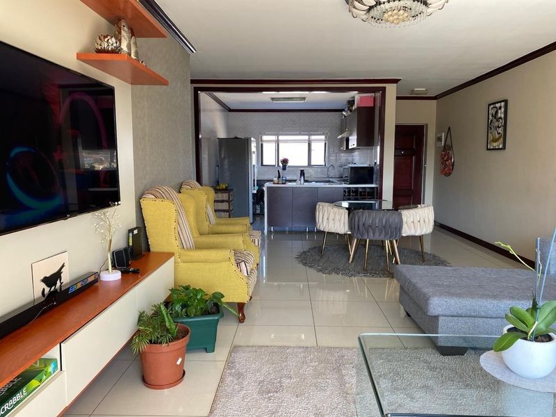 Spacious open-plan living and dining area flowing into a functional kitchen with modern cabinetry and tiled flooring throughout.