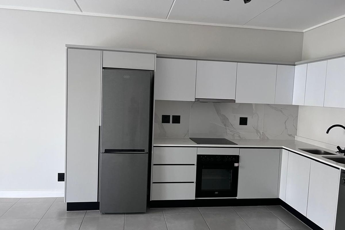 Modern kitchen featuring white cabinetry, stone countertops, marble-look splashback, integrated appliances, and sleek track lighting in a clean, contemporary finish.