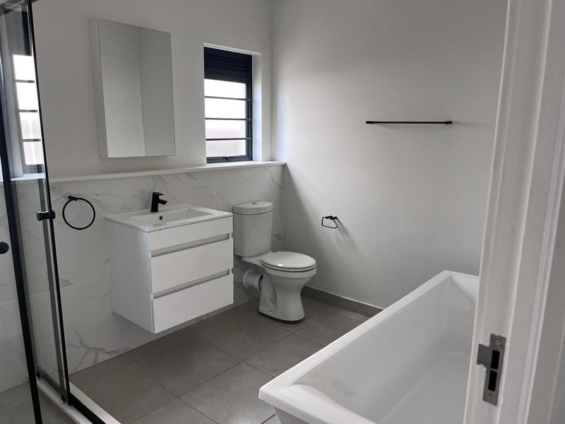 Modern, well-maintained bathroom featuring a wall-mounted vanity, freestanding bathtub, separate shower enclosure, and contemporary black fixtures with marble-look wall tiling.