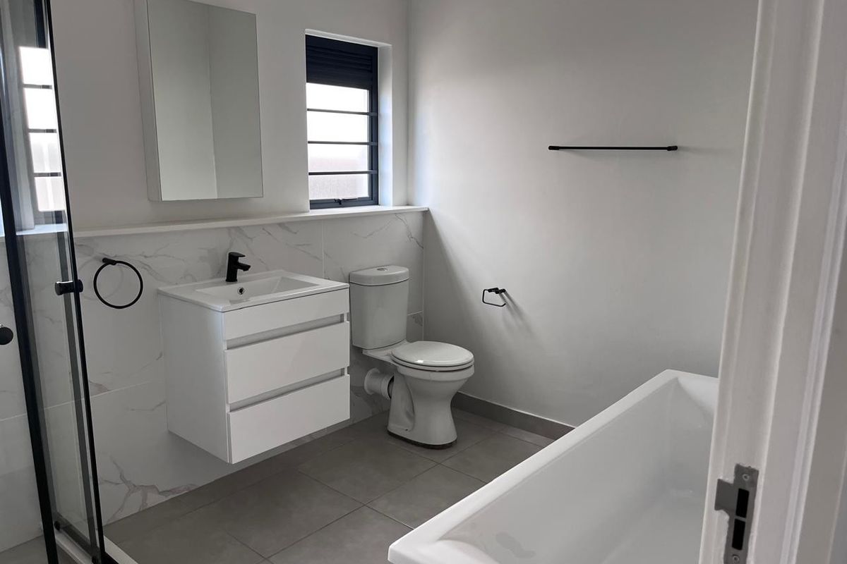 Modern, well-maintained bathroom featuring a wall-mounted vanity, freestanding bathtub, separate shower enclosure, and contemporary black fixtures with marble-look wall tiling.