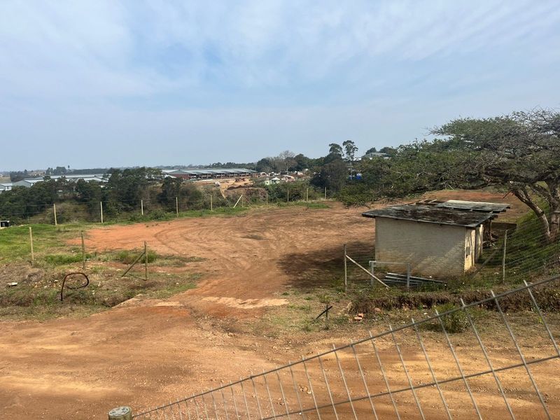 An elevated view of the vacant agricultural land featuring wire fencing and a small, weathered outbuilding structure.