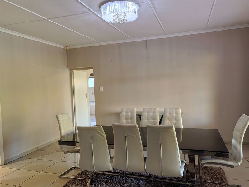 A dining room featuring tiled flooring, a decorative crystal chandelier, and coved ceiling details, providing a functional space for family meals.
