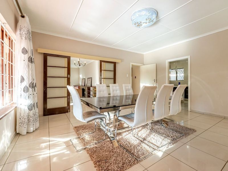 A bright dining room featuring tiled flooring, sliding wooden doors, and a modern flush mount ceiling light, offering a functional space for family meals.