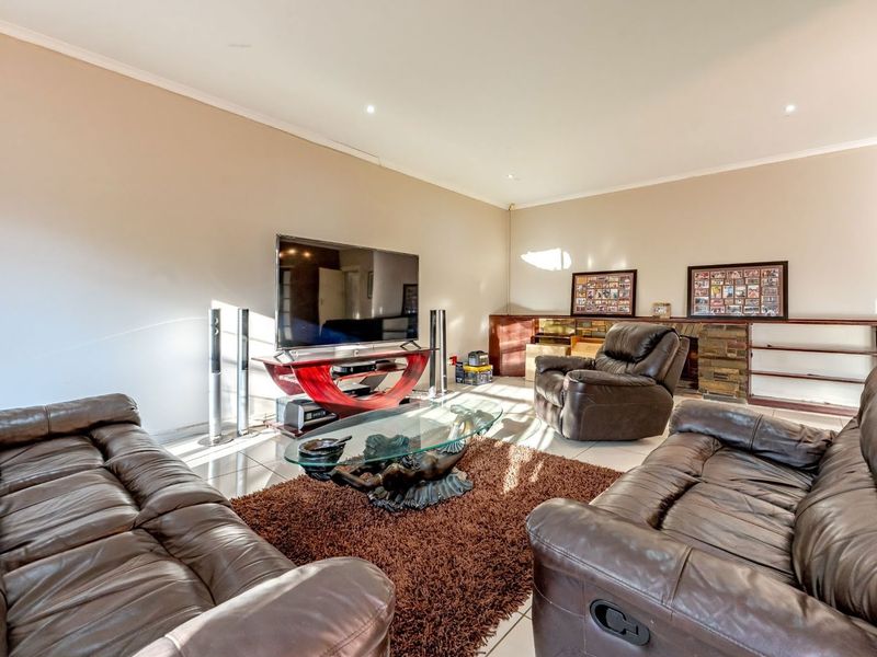 Spacious living room featuring tiled flooring, recessed downlights, and a stone-clad feature wall with built-in shelving.