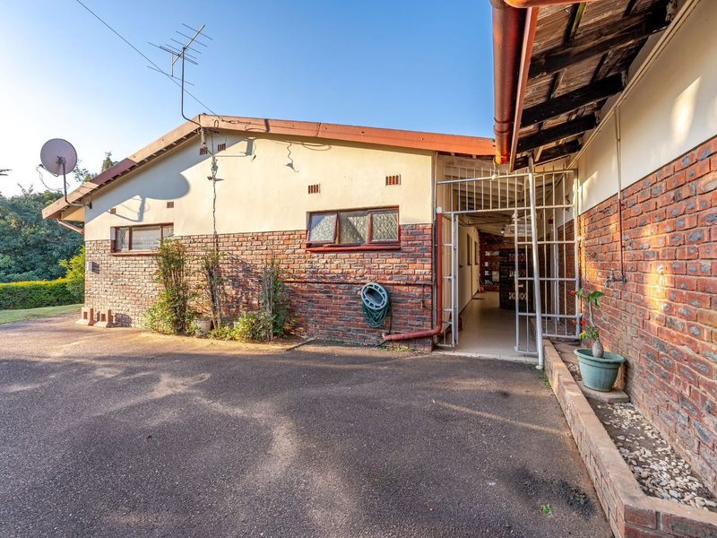 Rear exterior view of the property featuring a brick facade, asphalt driveway, and secure gated access point.