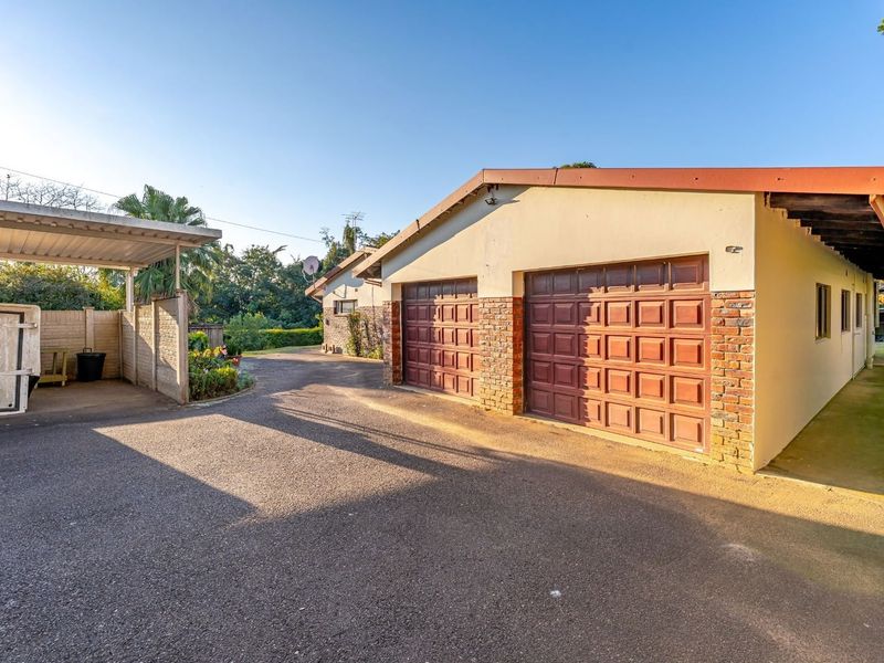Exterior view of a double garage with a side carport and paved driveway area.