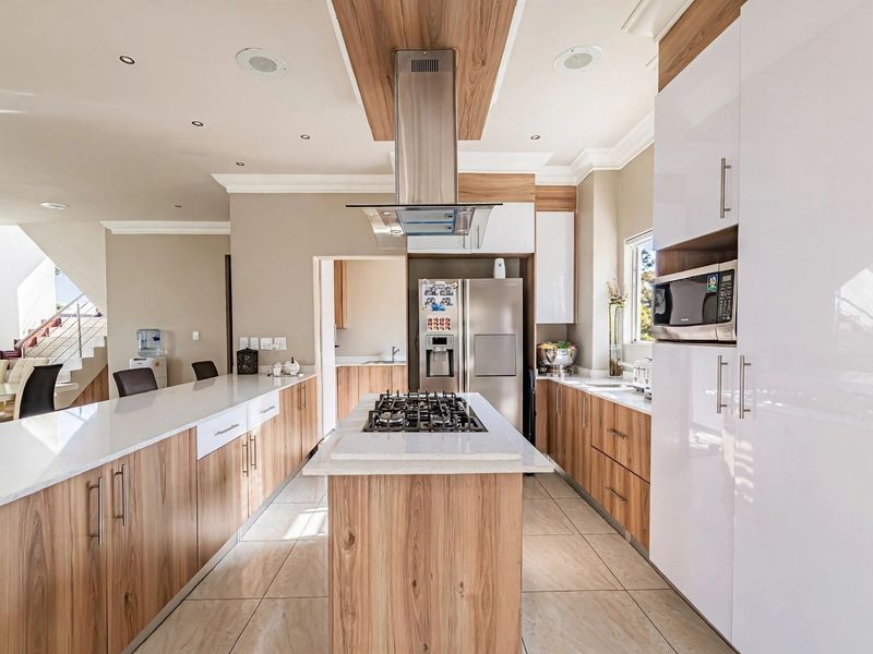 Modern kitchen featuring a central island with gas hob, stone countertops, high-gloss cabinetry, and integrated appliances, offering a sleek and functional culinary space.