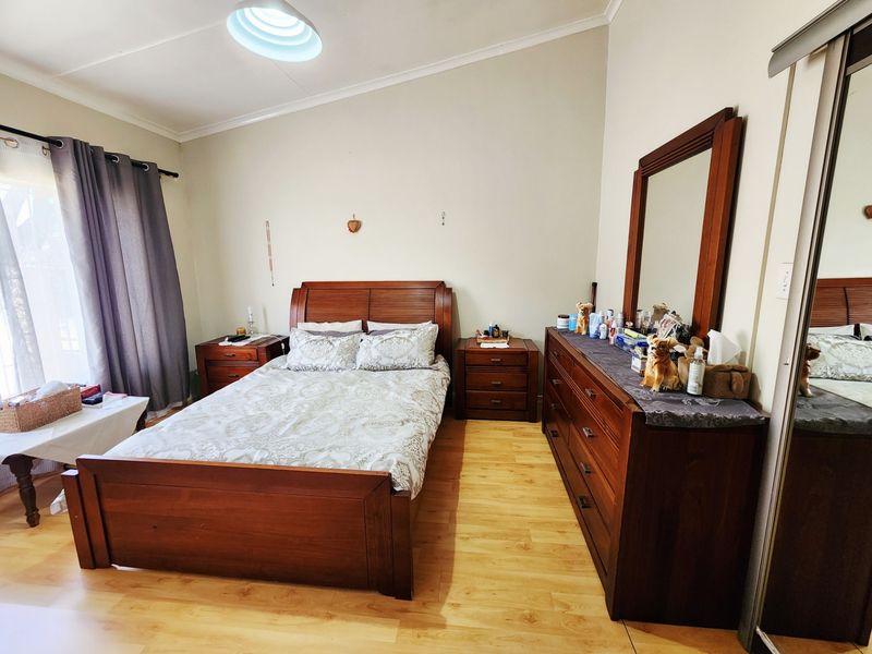 A well-lit bedroom featuring laminate flooring, a vaulted ceiling, and a built-in sliding door wardrobe.