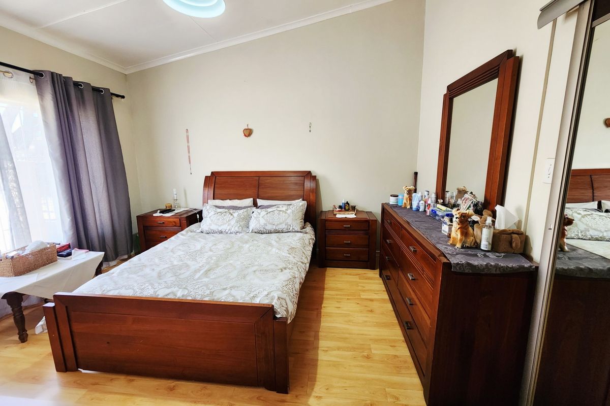 A well-lit bedroom featuring laminate flooring, a vaulted ceiling, and a built-in sliding door wardrobe.