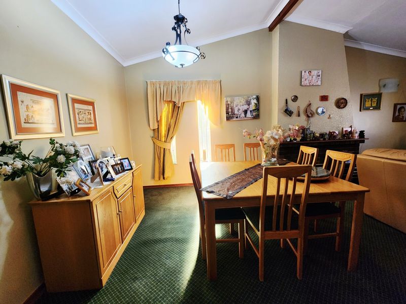 A dining room featuring a vaulted ceiling, a fireplace, and a central pendant light fixture, offering a traditional layout with carpeted flooring.