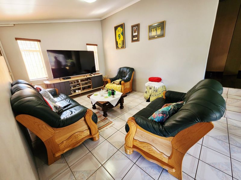 A comfortable living room featuring tiled flooring and natural light through windows fitted with security bars.