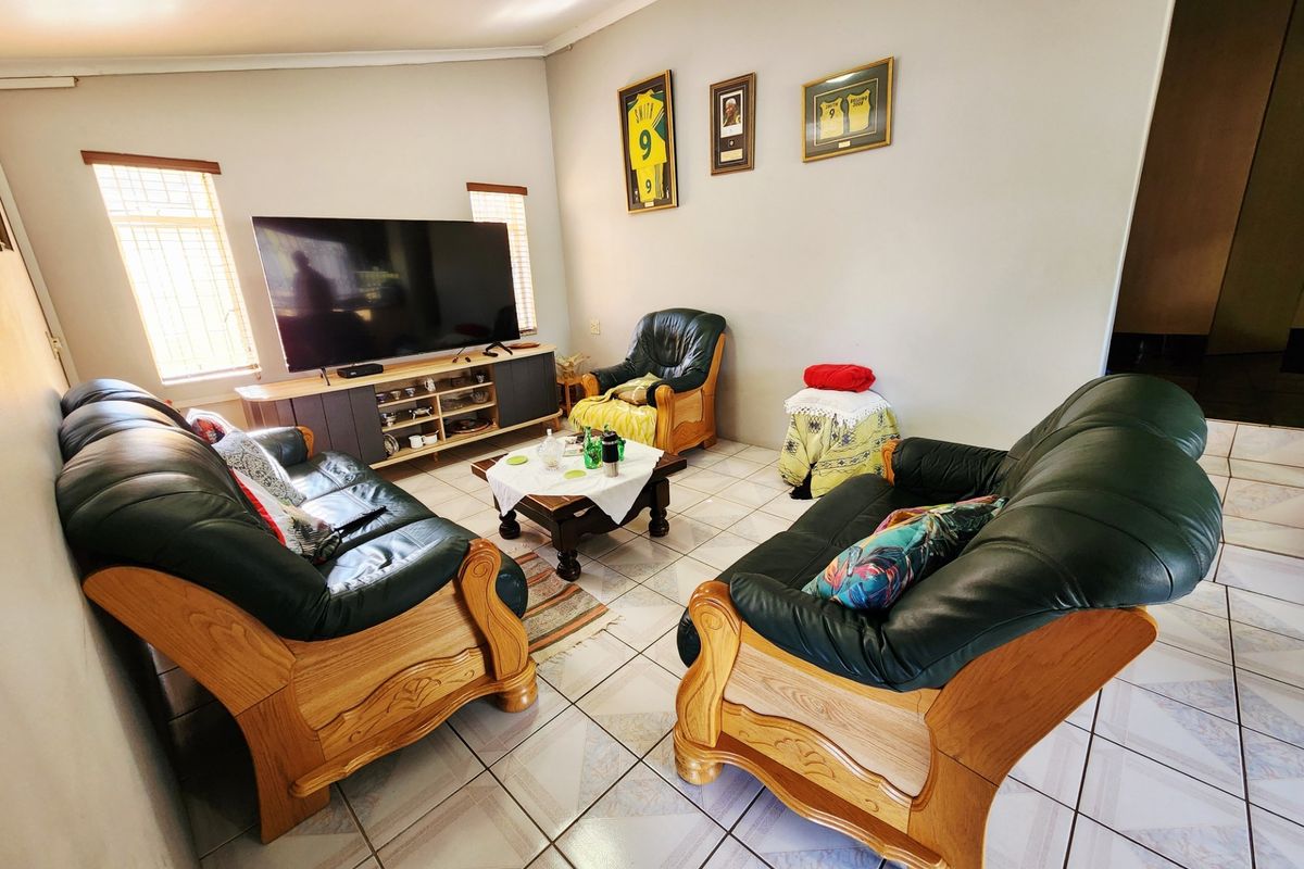 A comfortable living room featuring tiled flooring and natural light through windows fitted with security bars.