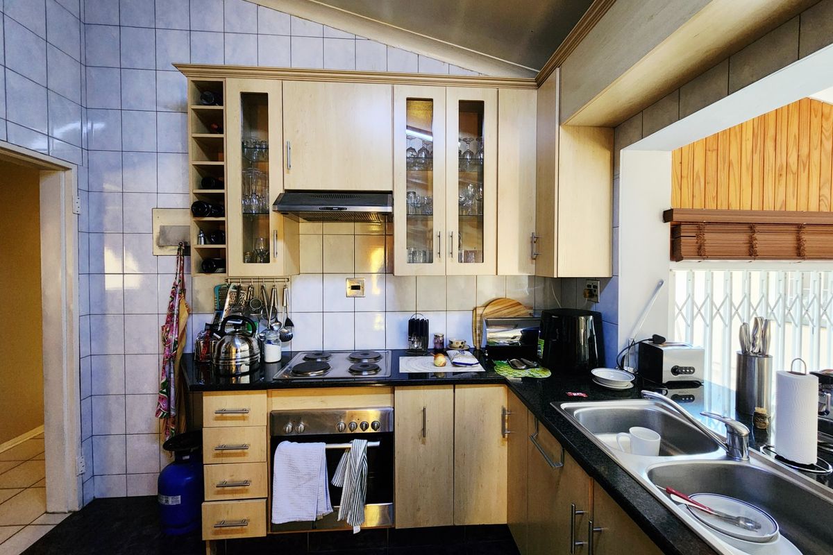 A functional kitchen featuring light wood cabinetry, granite countertops, a built-in oven with electric hob, and a double stainless steel sink.