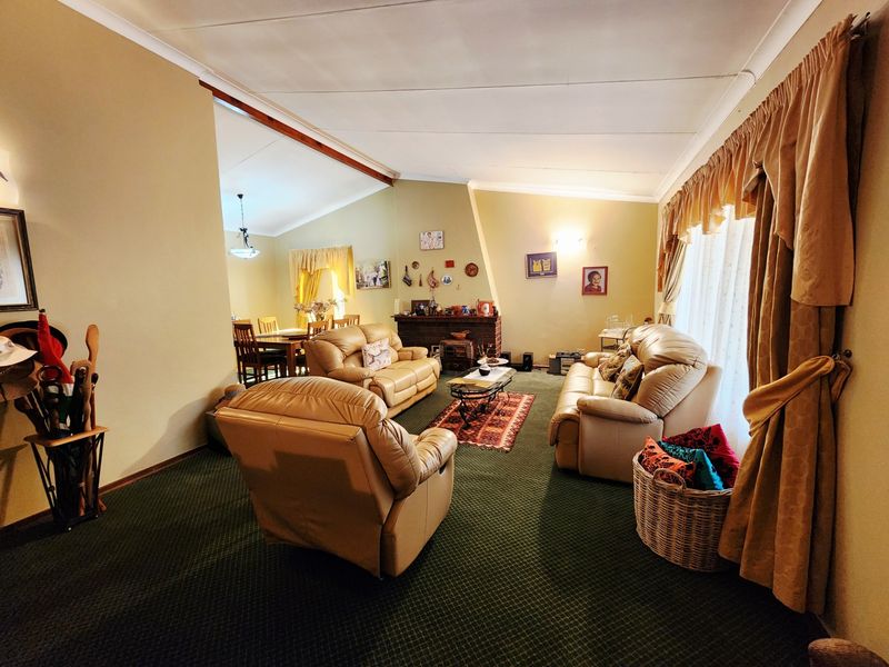 Spacious open-plan living and dining area featuring a brick fireplace, coved ceilings, and wall-to-wall carpeting, offering a comfortable and traditional layout.