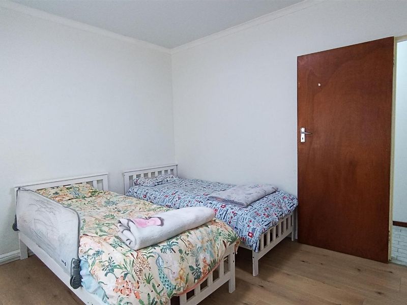 A functional bedroom featuring laminate flooring and a solid wood door, providing a neutral base for personalization.