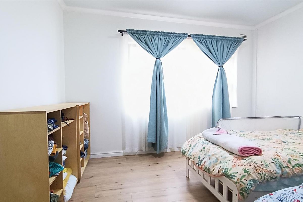 A bright bedroom featuring light-toned laminate flooring and neutral walls, providing a clean and functional space.