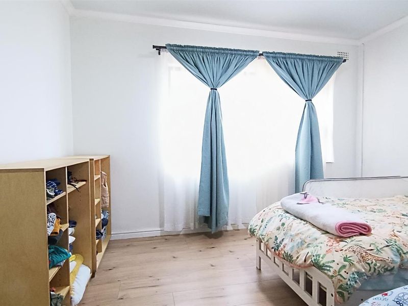 A bright bedroom featuring light-toned laminate flooring and neutral walls, providing a clean and functional space.