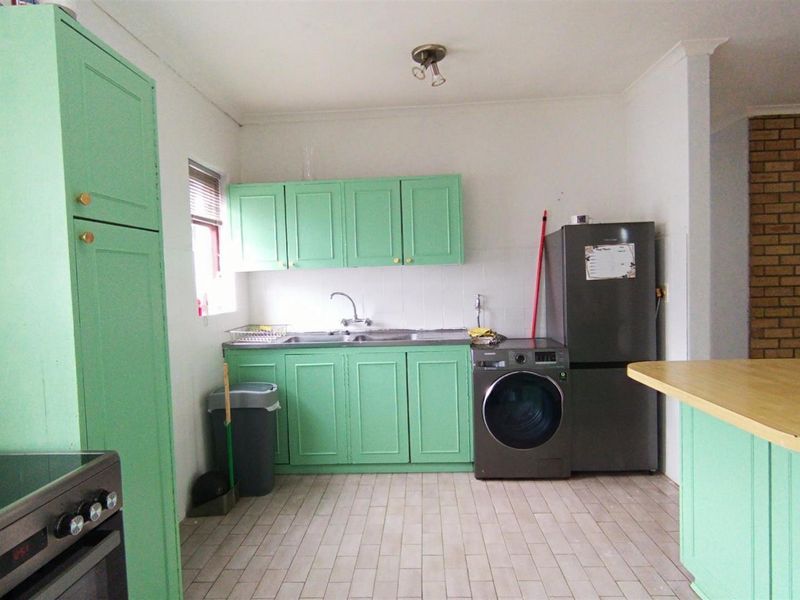 A functional kitchen featuring mint green cabinetry, tiled flooring, a stainless steel sink, and a built-in oven with a tiled backsplash.