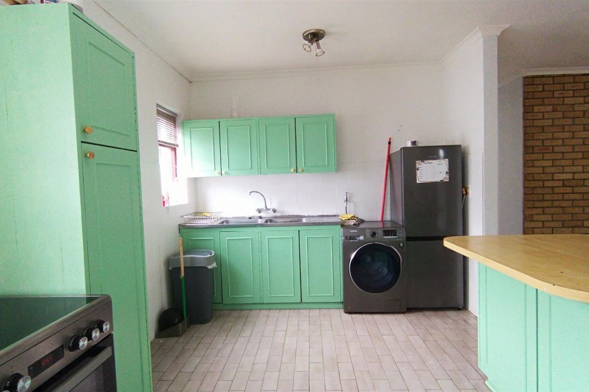 A functional kitchen featuring mint green cabinetry, tiled flooring, a stainless steel sink, and a built-in oven with a tiled backsplash.