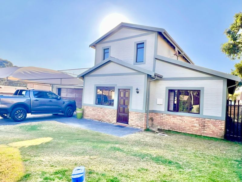 Front view of a two-story residential house featuring a brick and painted facade, paved driveway, and attached carport.