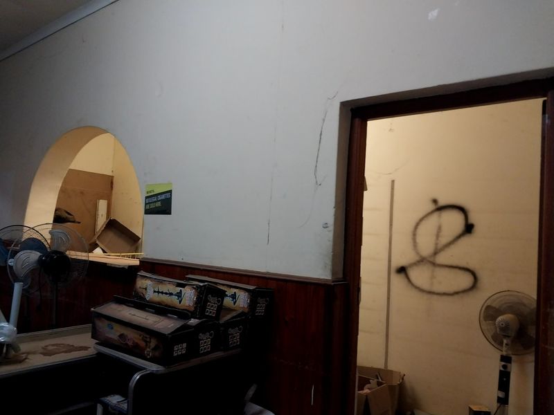 Interior utility space featuring an arched service opening and timber wainscoting, currently showing signs of wear including wall cracks and graffiti.