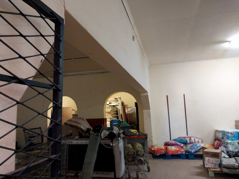 A utilitarian retail storage area featuring arched architectural openings and structural beams, currently used for inventory management.