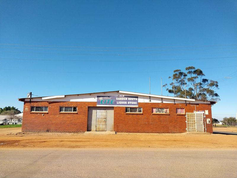 Front elevation of a single-story retail building featuring face brick construction, metal roller shutter access, and security gates.