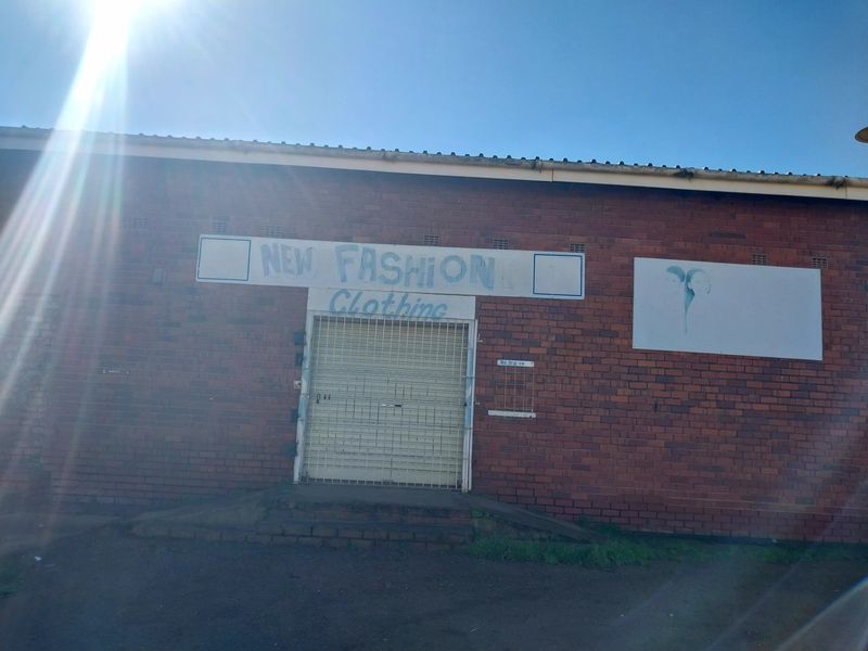 Front elevation of a retail property featuring a brick facade, security roller shutter entrance, and existing signage.
