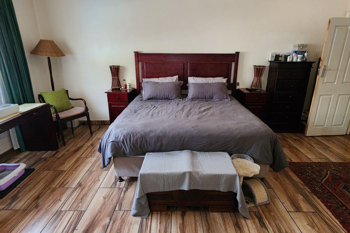A spacious bedroom featuring wood-look tile flooring and a classic panel door, offering a functional layout with ample space for bedroom furniture.