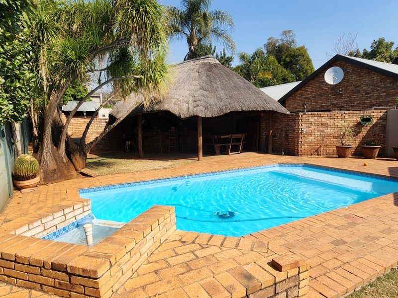 Outdoor pool area featuring a swimming pool, brick paving, and a traditional thatched lapa, perfect for outdoor entertaining.