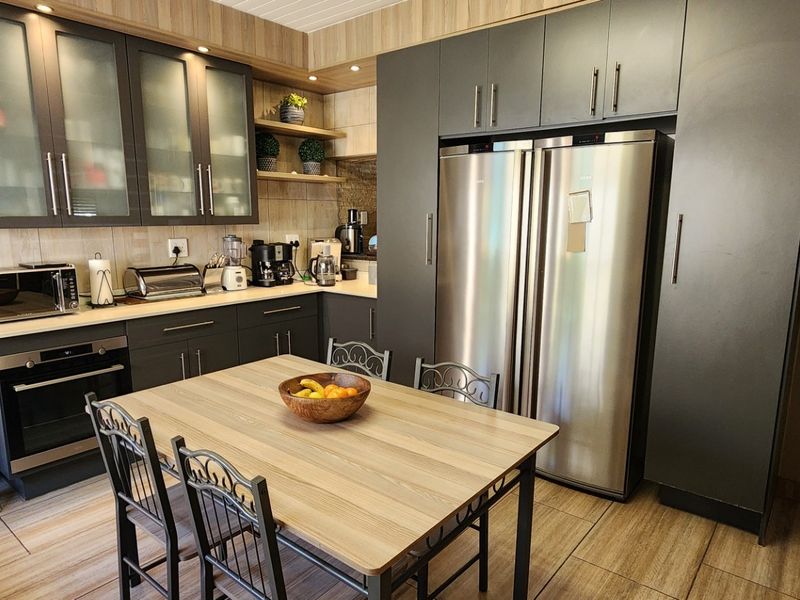 Modern kitchen featuring dark cabinetry, integrated oven, stone countertops, and tiled flooring, offering a functional and contemporary cooking space.