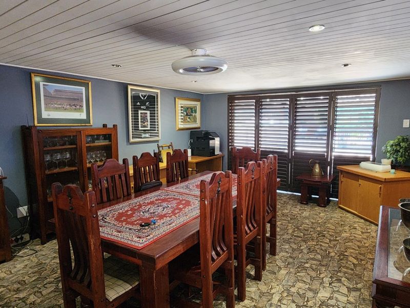 A dining room featuring a timber-slat ceiling, recessed lighting, and timber plantation shutters, providing a traditional aesthetic.