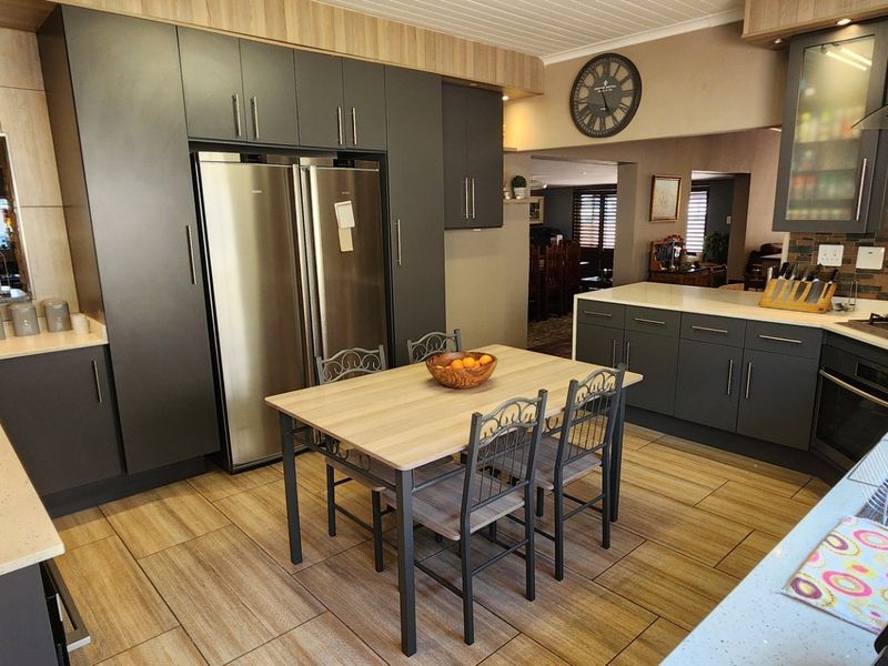 Modern kitchen featuring dark cabinetry, stone countertops, gas hob, built-in oven, and tiled flooring, offering a functional and stylish cooking space.