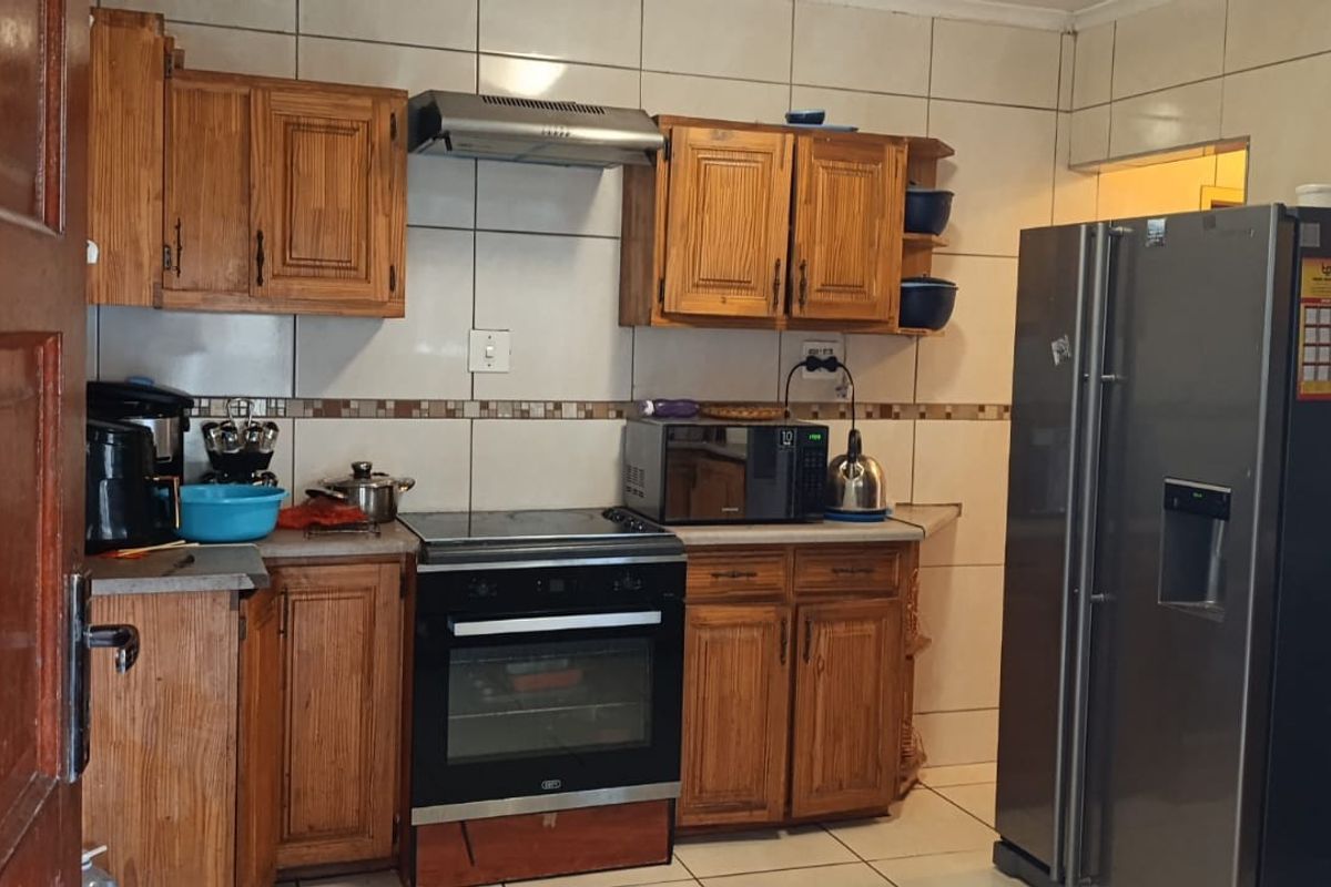 A functional kitchen featuring wooden cabinetry, tiled backsplash, and built-in cooking appliances, offering a classic layout with ample storage space.