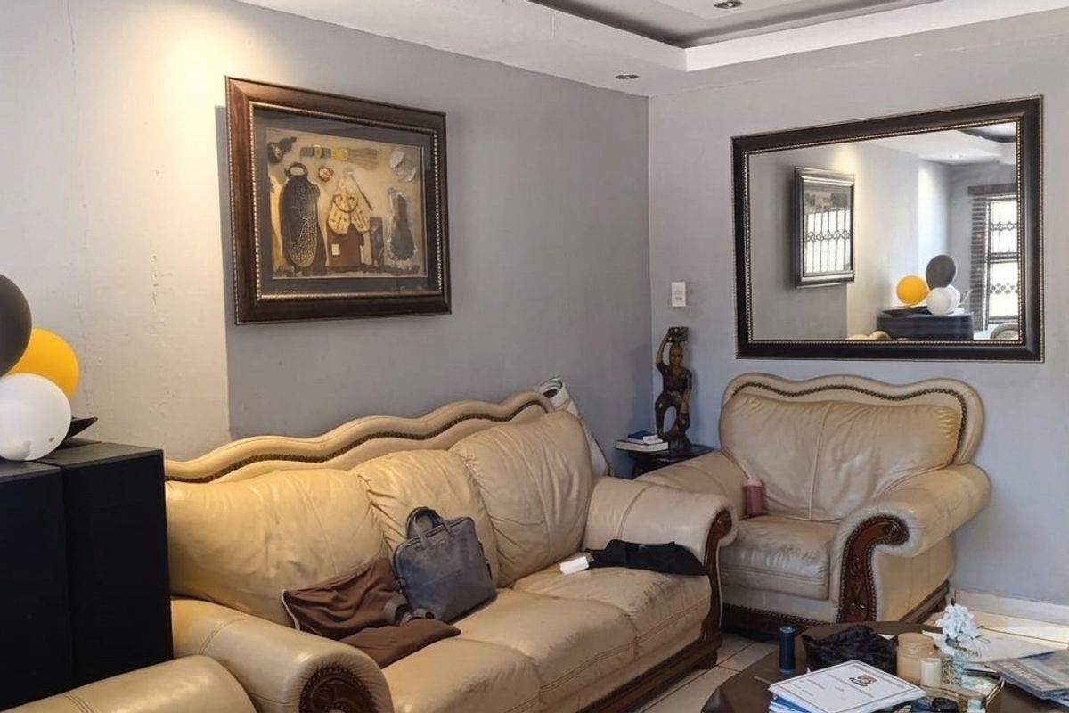 A living room featuring tiled flooring, recessed ceiling lighting, and an arched entryway leading to an adjacent space.