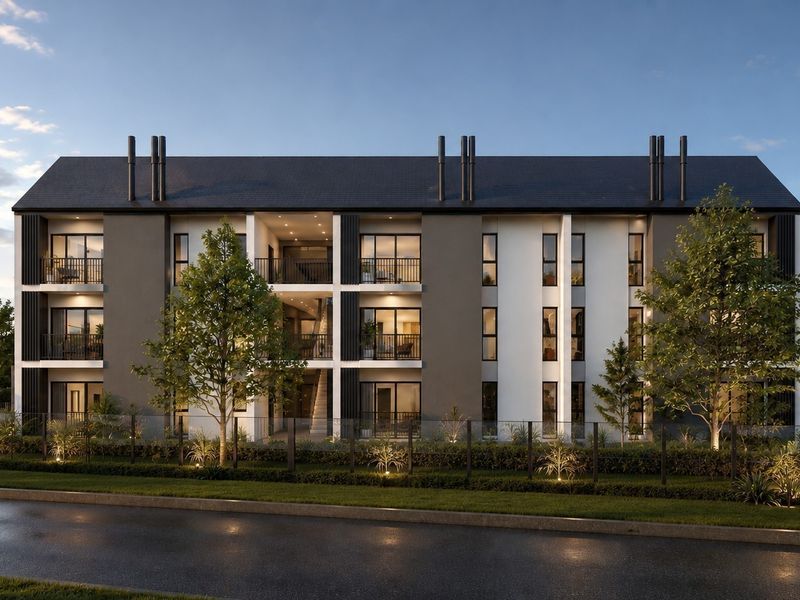 Modern multi-story apartment building featuring a contemporary facade, private balconies, pitched roof design, and landscaped grounds with paved parking areas.