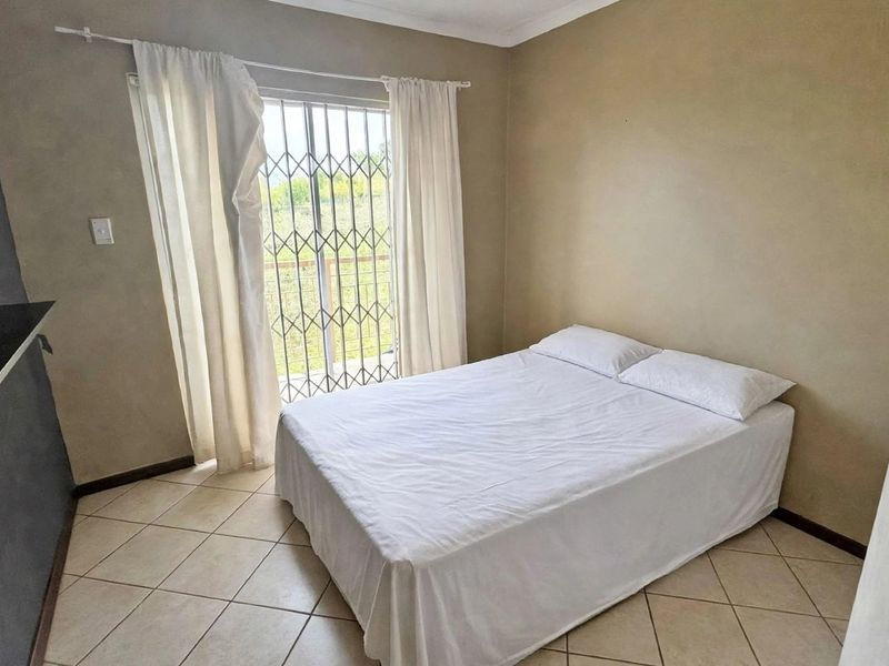 A bedroom featuring tiled flooring, a built-in cupboard, and a sliding glass door with a security gate leading to an outdoor area.