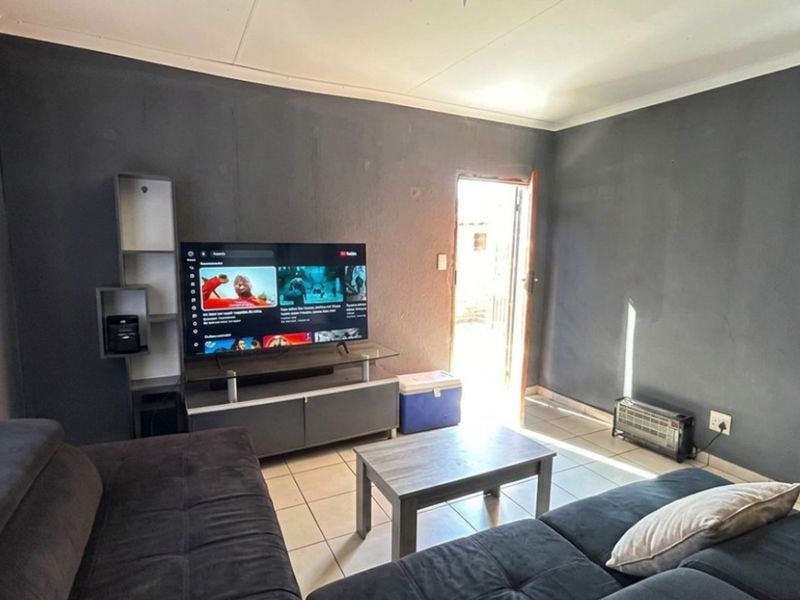 A living room featuring tiled flooring, dark painted walls, and direct access to an exterior area.