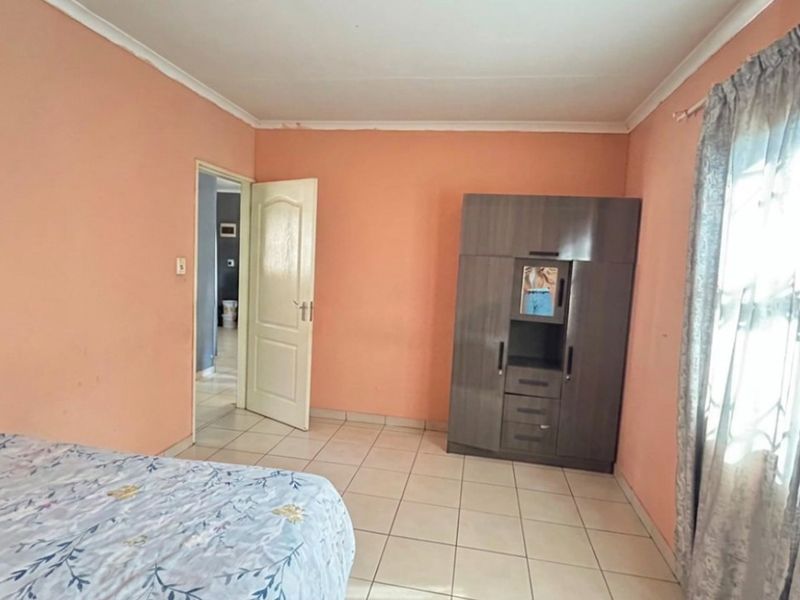 A bedroom featuring tiled flooring and a built-in cupboard, offering a functional space ready for cosmetic updates and personalization.