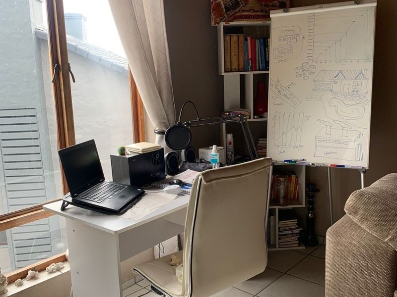 A functional home office space featuring tiled flooring and a large timber-framed window providing natural light.