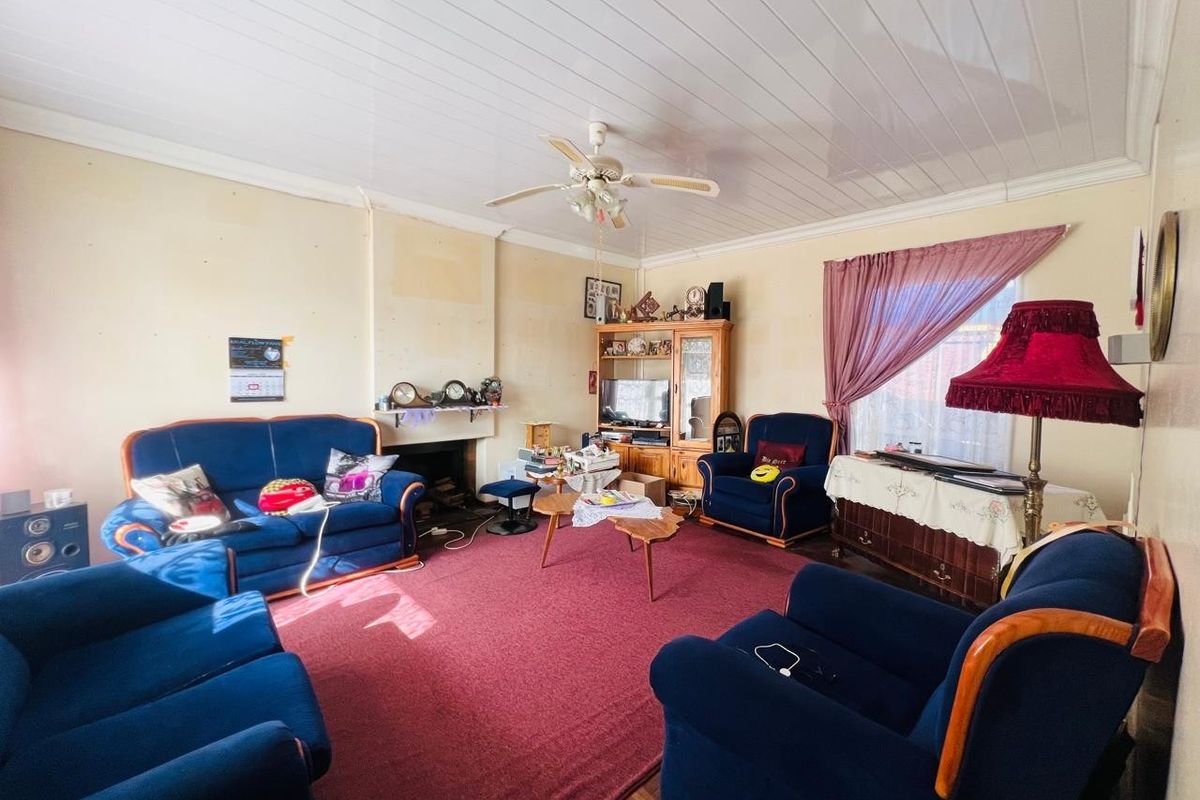 A spacious living room featuring a fireplace, ceiling fan, and tongue and groove ceiling, offering a traditional layout ready for modern updates.