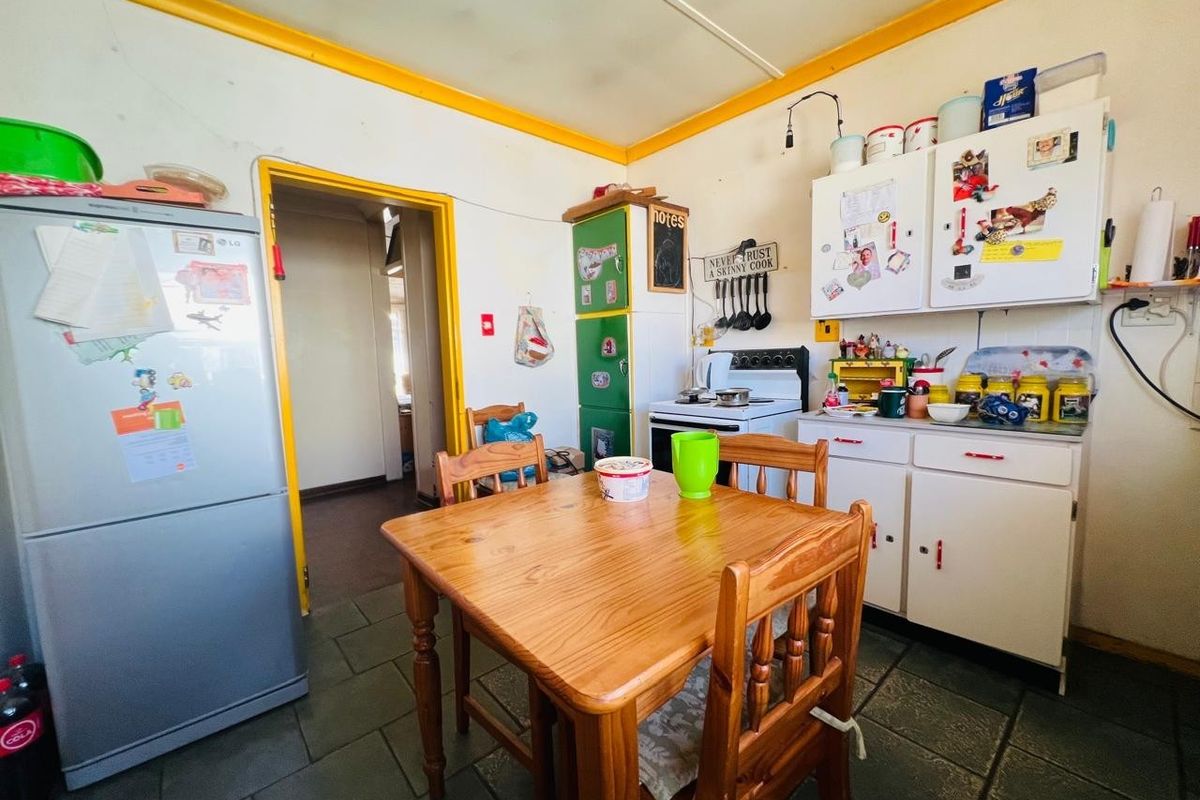 A dated kitchen featuring tiled flooring, built-in cabinetry, and a freestanding stove, offering significant potential for modernization and renovation.