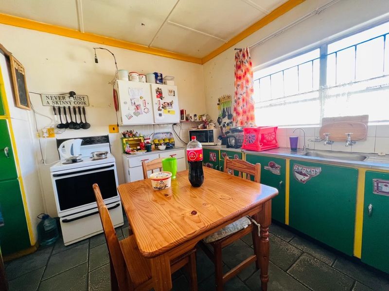 A dated kitchen featuring original cabinetry, a freestanding stove, and a stainless steel sink, offering significant potential for a modern renovation.