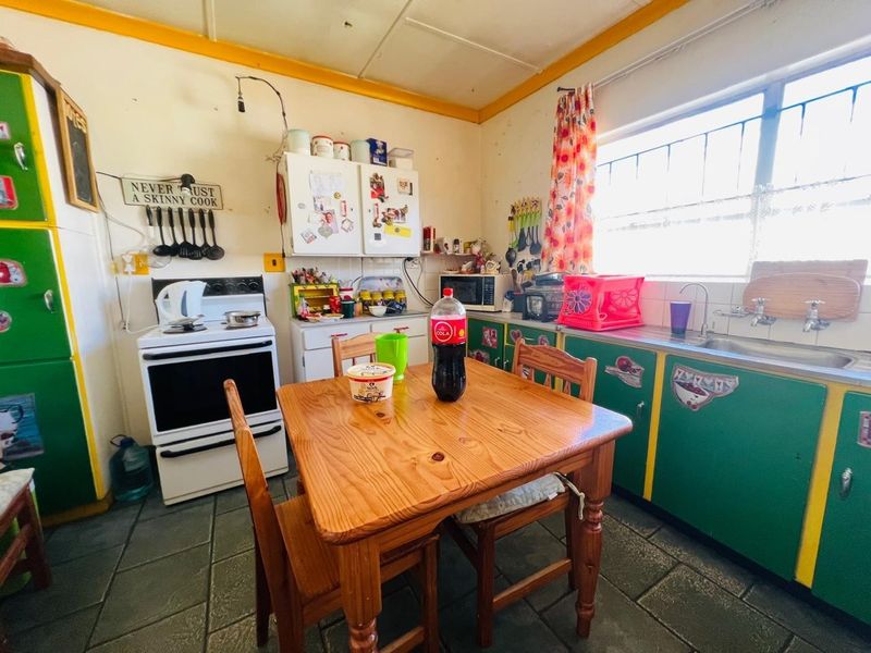 A dated kitchen featuring original cabinetry, a freestanding stove, and tiled flooring, offering significant potential for modernization and renovation.