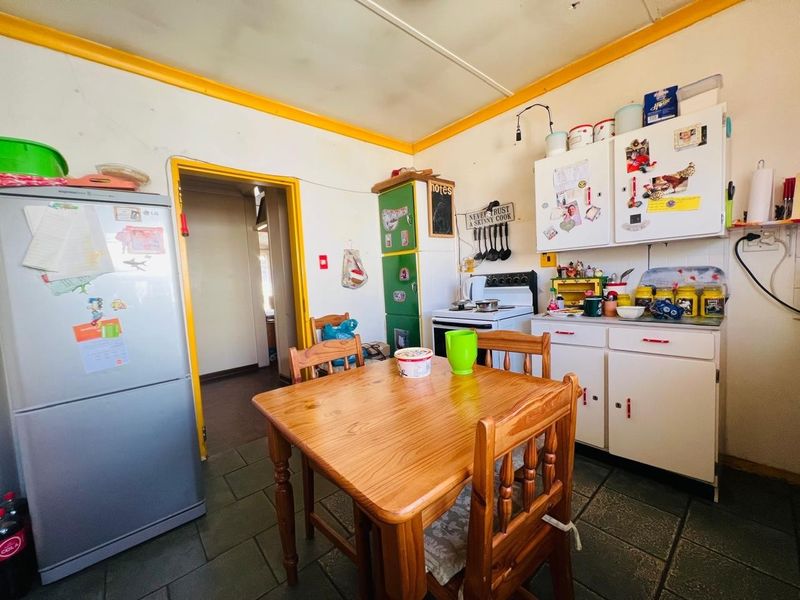 A dated kitchen area featuring tiled flooring, built-in cabinetry, and a freestanding stove, offering potential for modernization and renovation.
