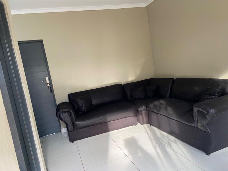 A simple living room area featuring neutral wall paint and light-colored floor tiles, providing a clean and functional space.