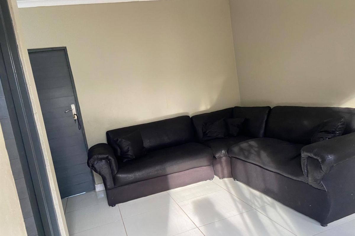A simple living room area featuring neutral wall paint and light-colored floor tiles, providing a clean and functional space.