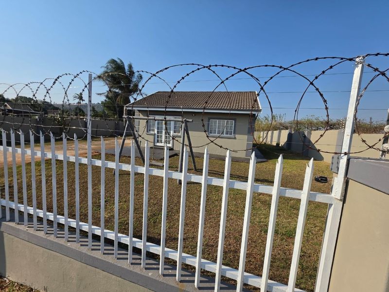 Rear view of the property featuring a tiled roof, french doors leading to a concrete patio, and secure perimeter fencing with razor wire.