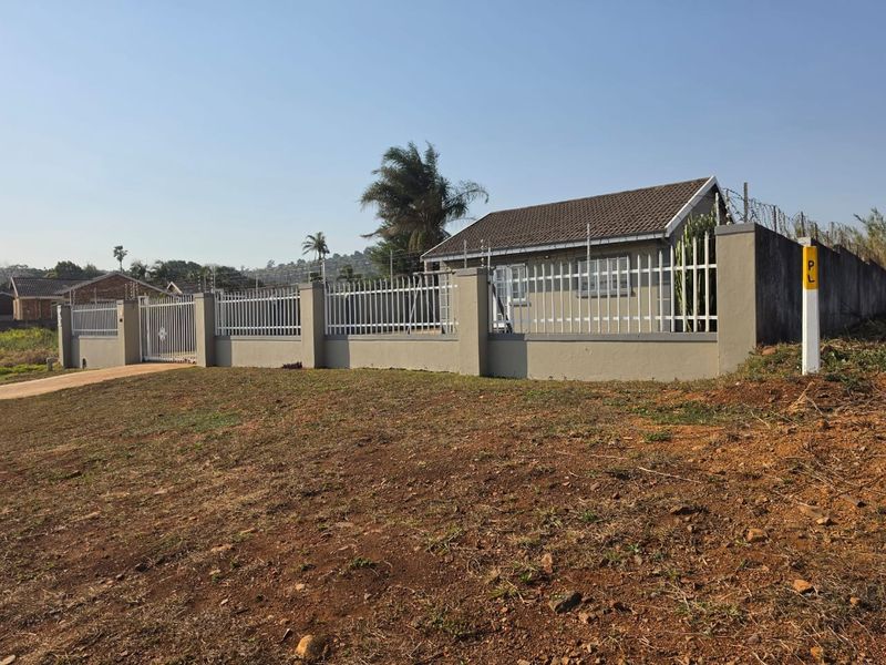 Front exterior view of the property featuring a secure perimeter wall with metal fencing, electric security wires, and a tiled roof structure.